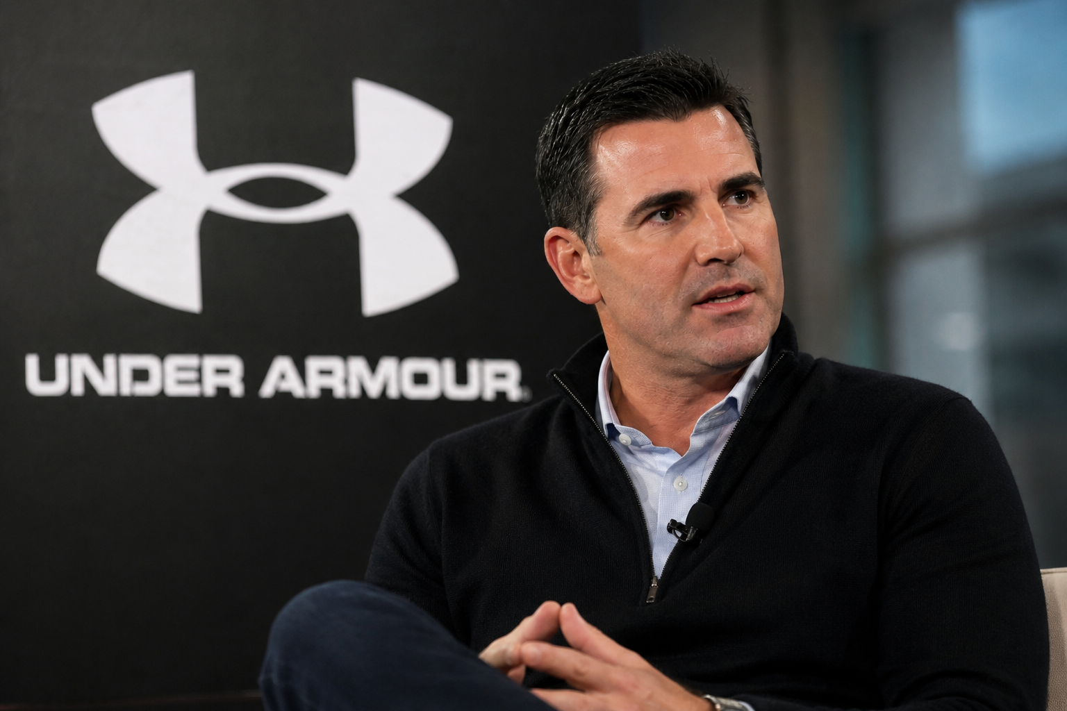 Kevin Plank speaks during an interview with the Under Armour logo behind him